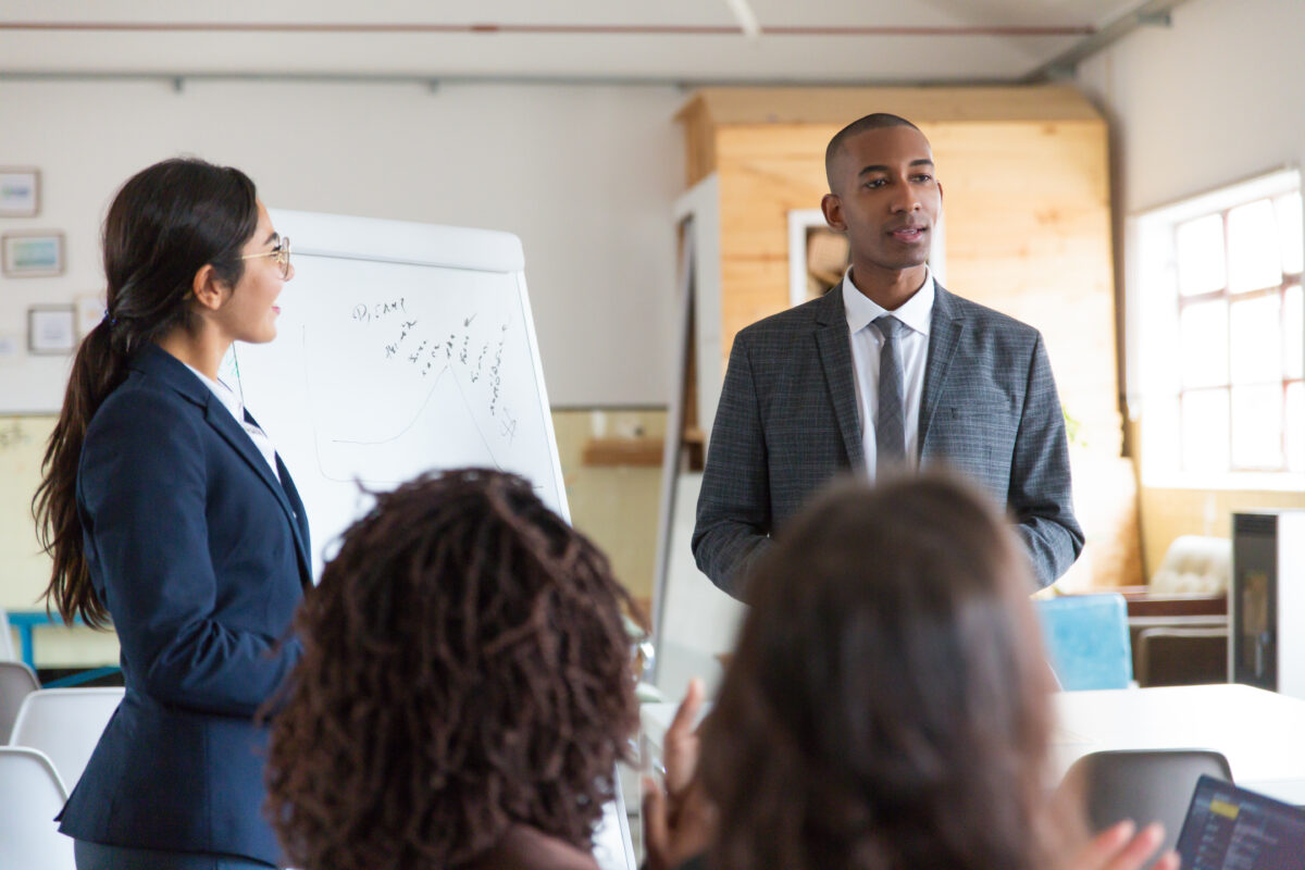 cheerful young speakers standing near whiteboard