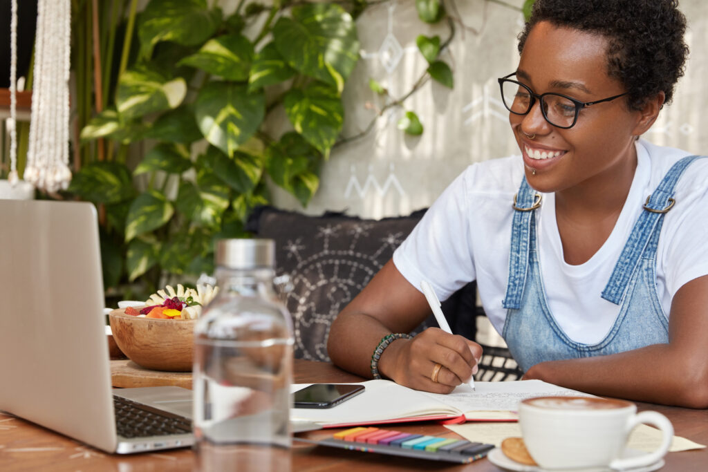 glad dark skinned woman watches webinar online focused into laptop computer