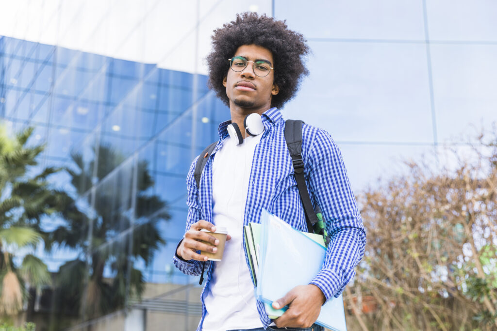 portrait young male afro american student carrying bag shoulder books hand standing against university building