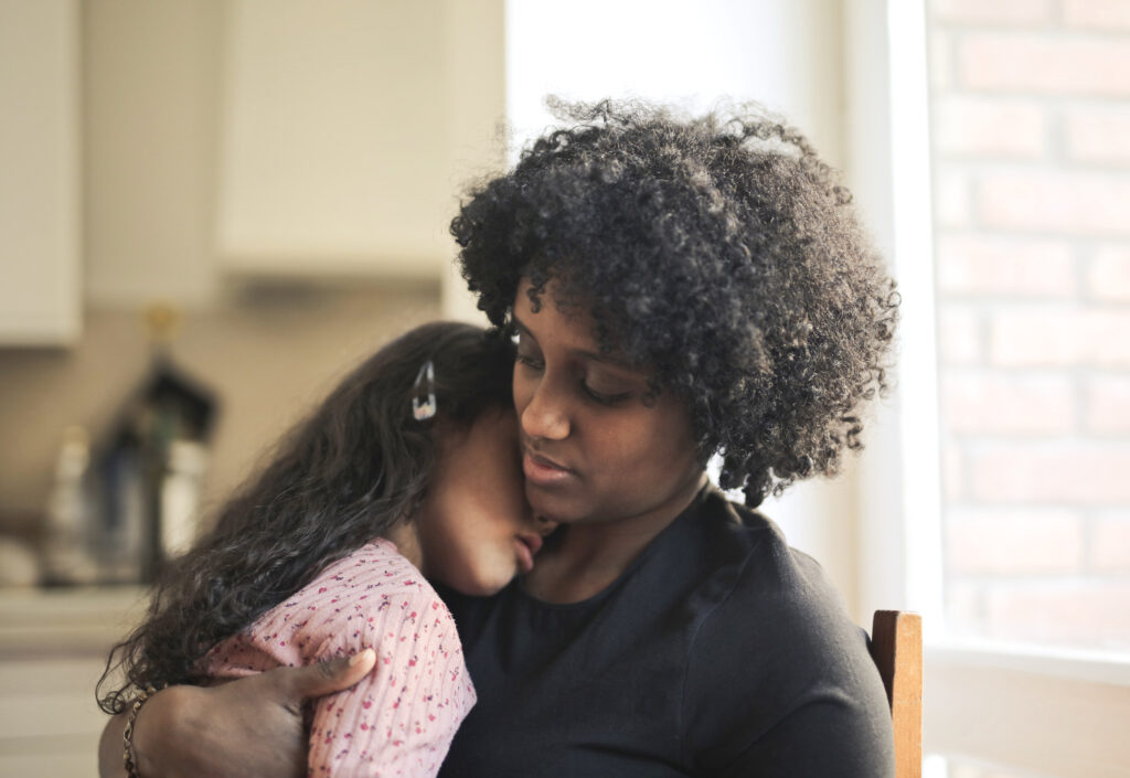 shallow focus tired multi racial kid hugging her black mother home